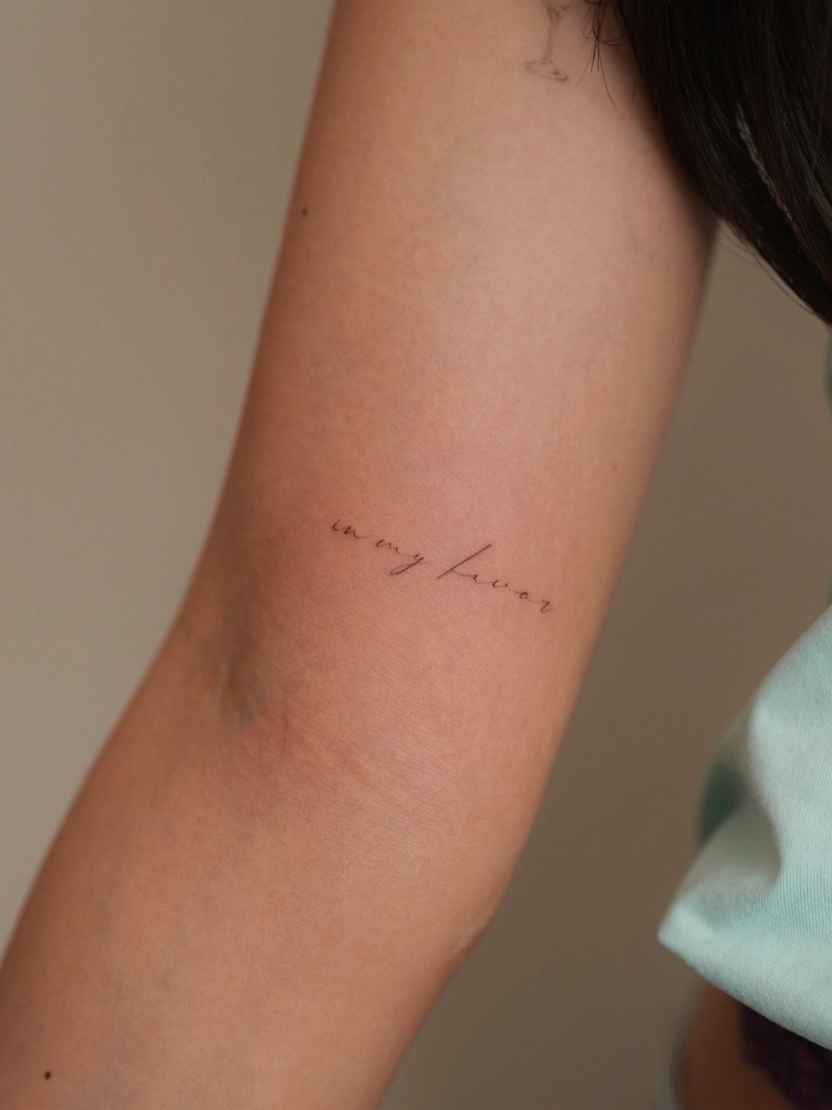 Cursive handwriting tattoo on the inner forearm of a person.