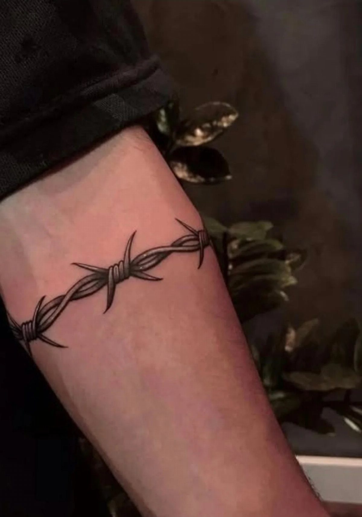 Barbed wire tattoo wrapping around the inner bicep of a man's arm.
