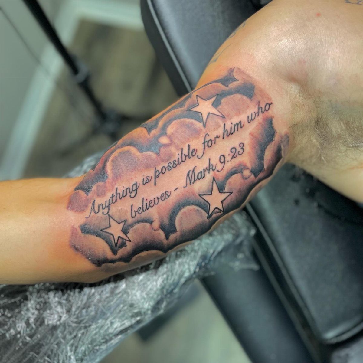 Inner bicep tattoo with Bible verse Mark 9:23 among clouds and stars.