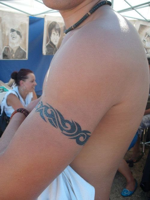 Tribal pattern armband tattoo on the inner bicep of a man's arm.