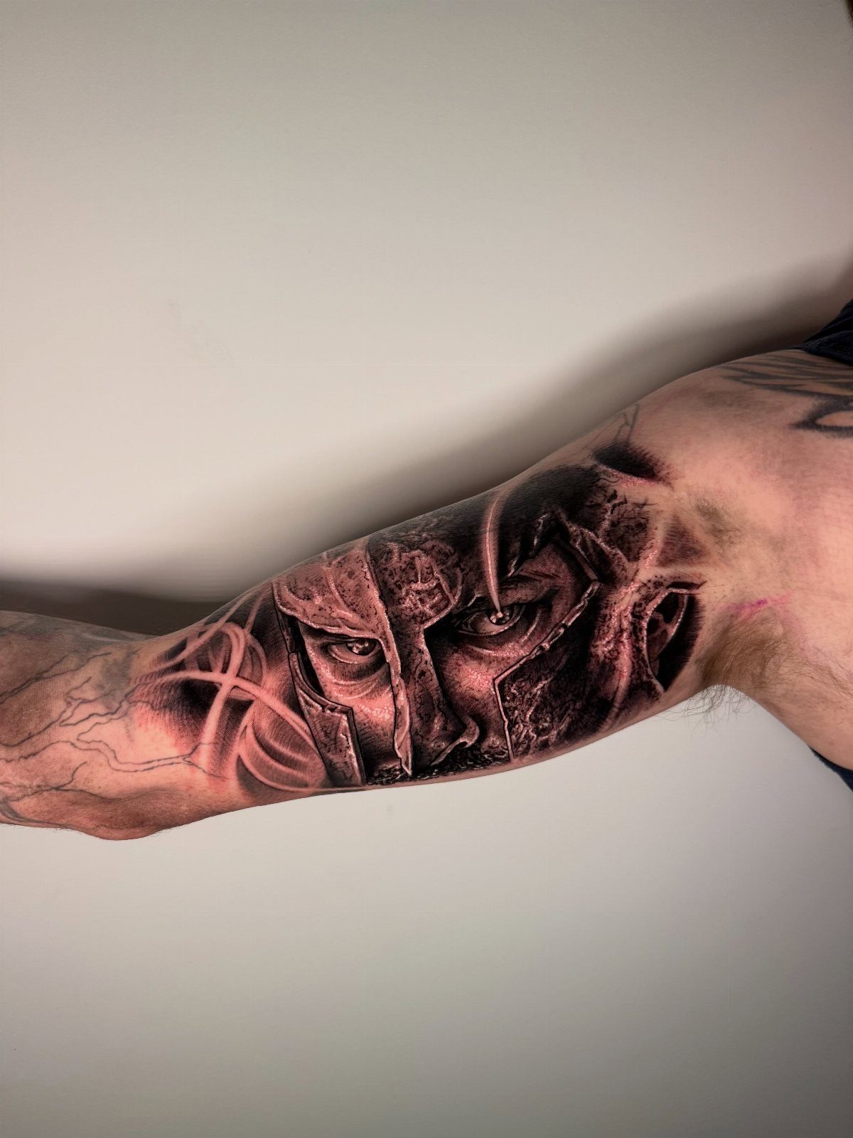 Detailed realism tattoo of a Spartan warrior on a person's inner bicep.