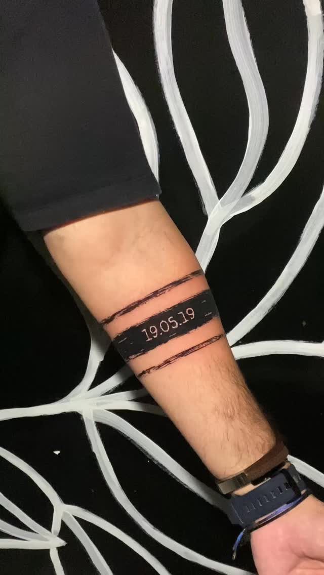Armband tattoo on a forearm with a black band and date 19.05.19