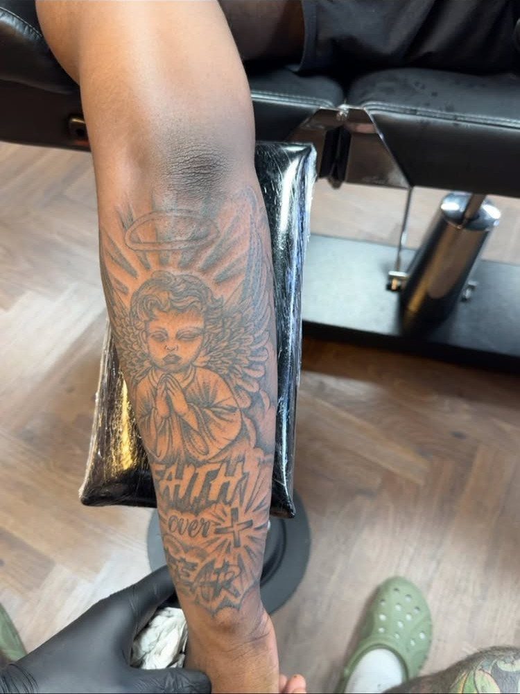 Inner forearm tattoo of a praying angel with a halo and wings.