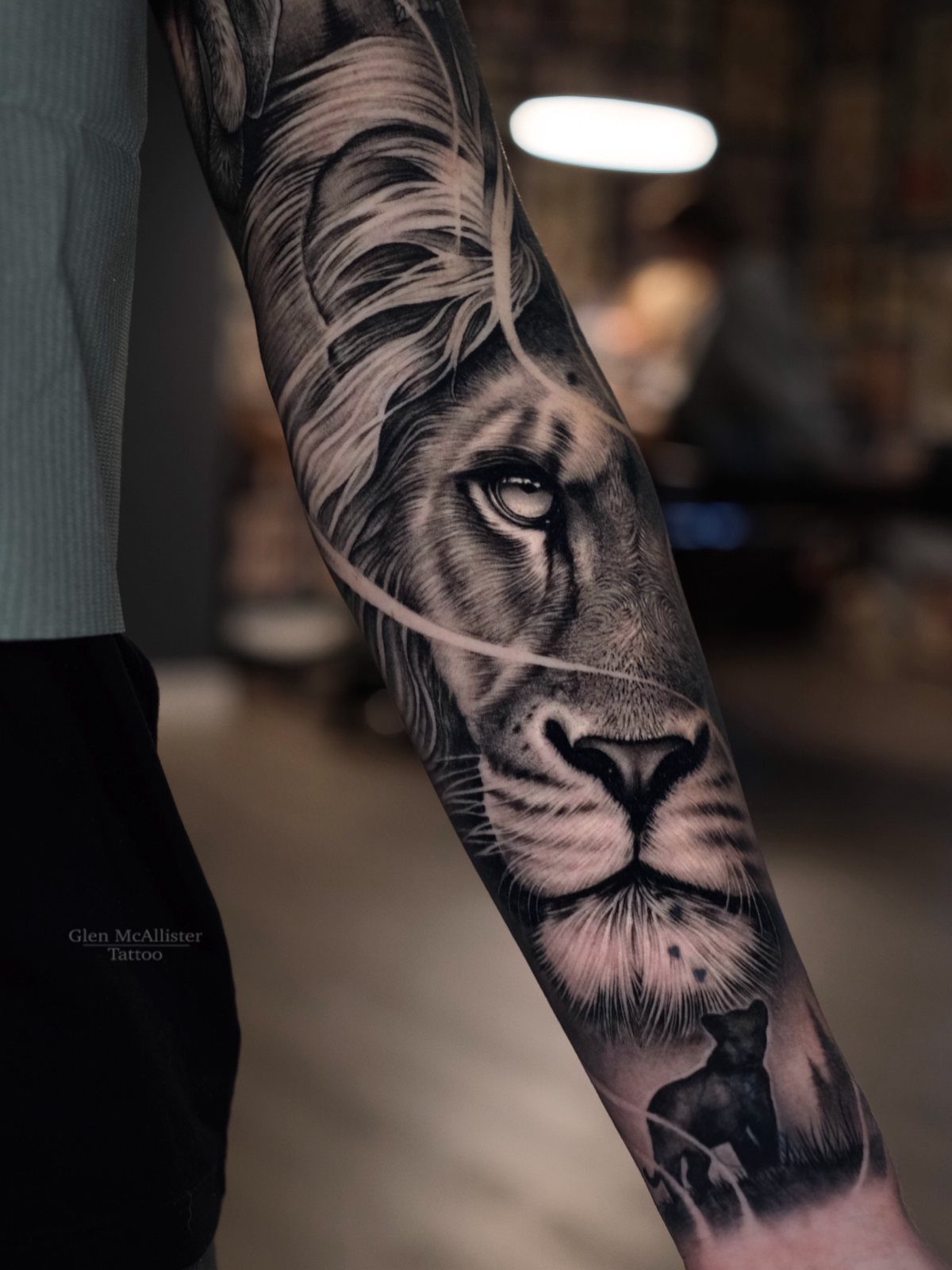 Lion realism tattoo on a person's inner forearm in black and grey ink.