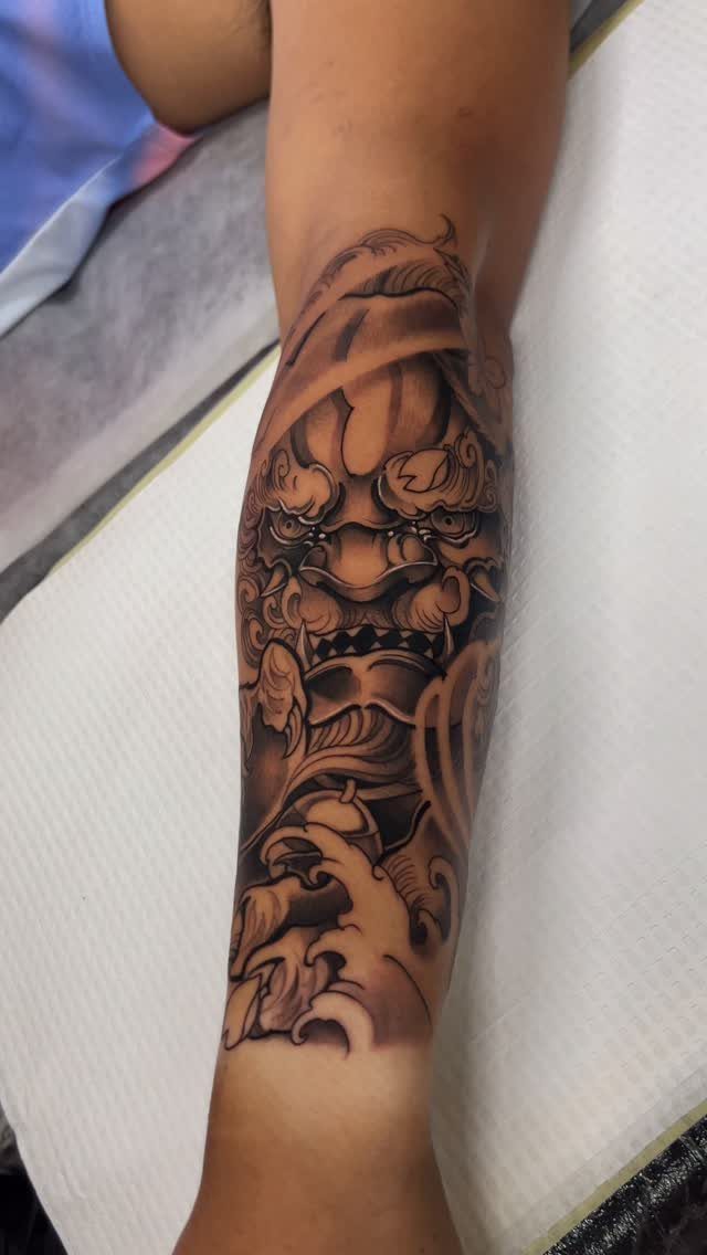 Japanese Foo Dog tattoo on a man's lower leg in black and grey ink