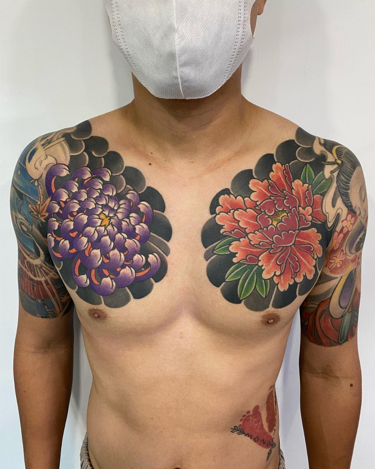 Man with traditional Japanese hikae chest tattoos featuring purple and red flowers.