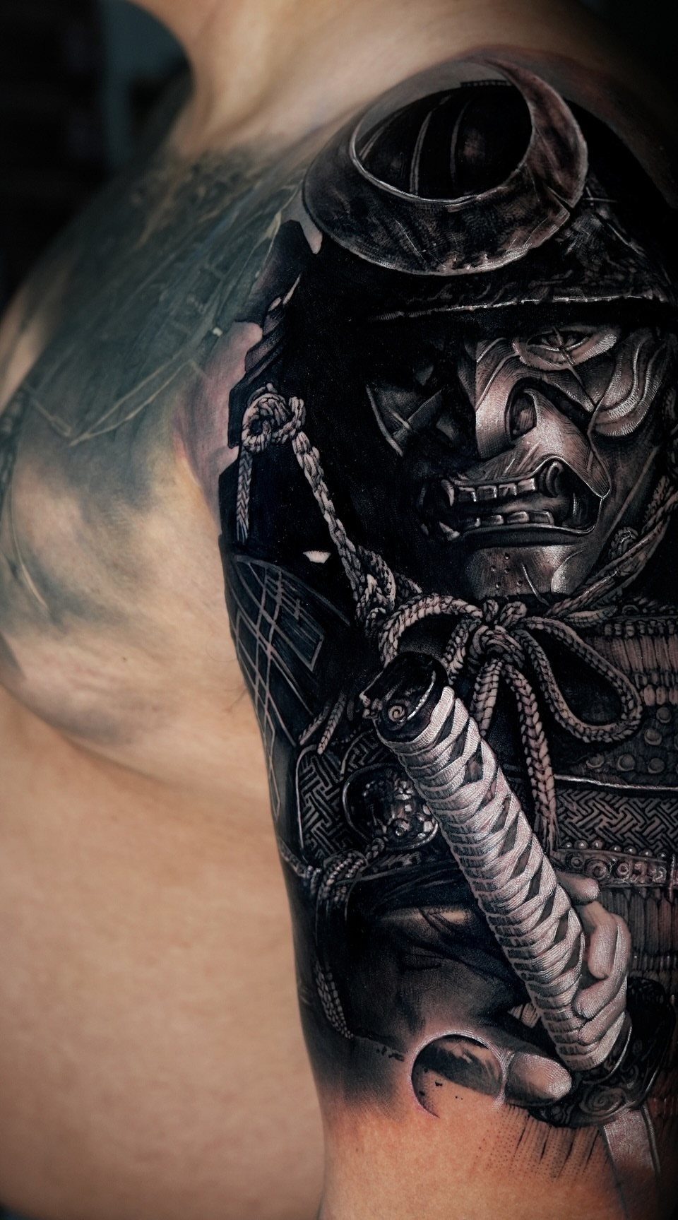Samurai tattoo on a man's arm featuring a helmeted warrior and katana