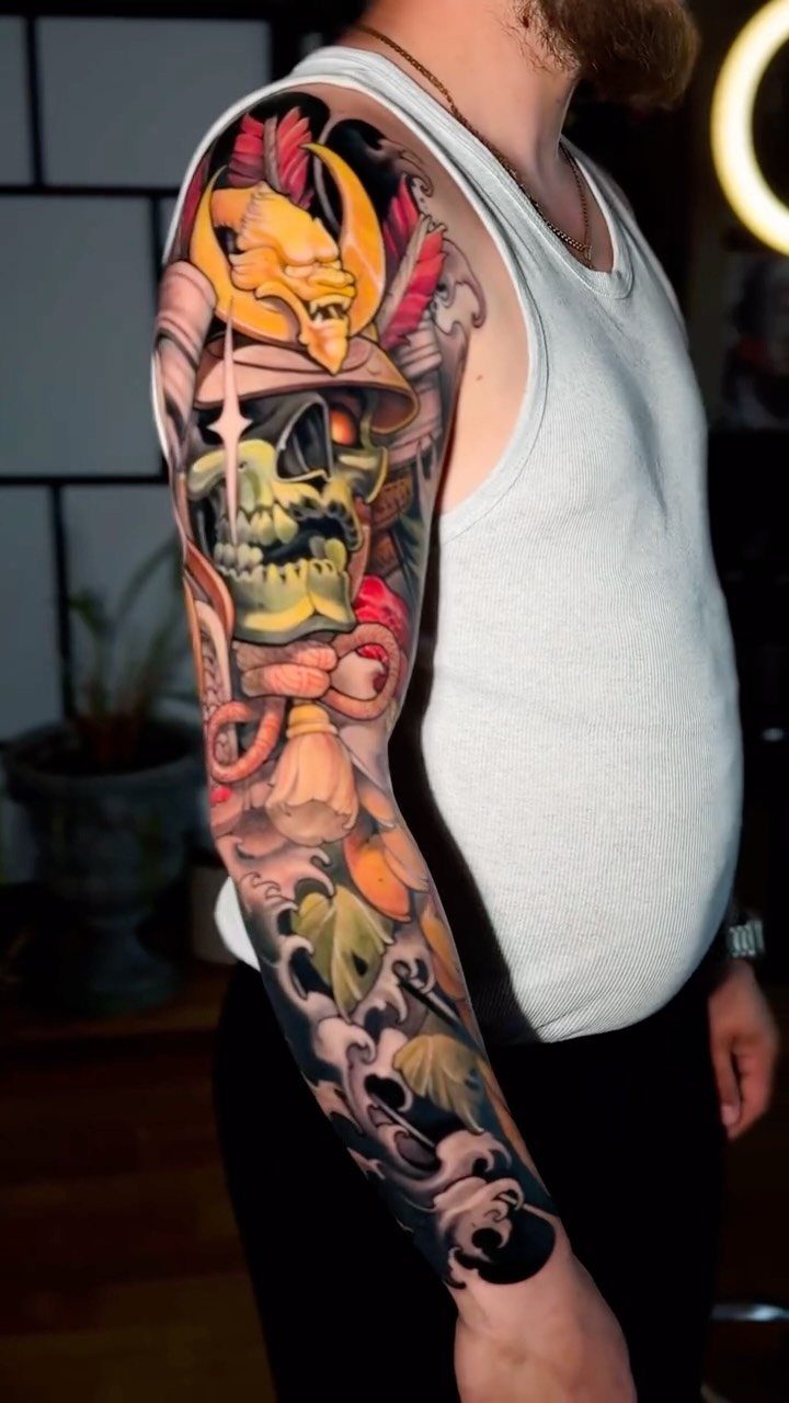 Japanese style sleeve tattoo featuring a green skull and yellow demon mask.
