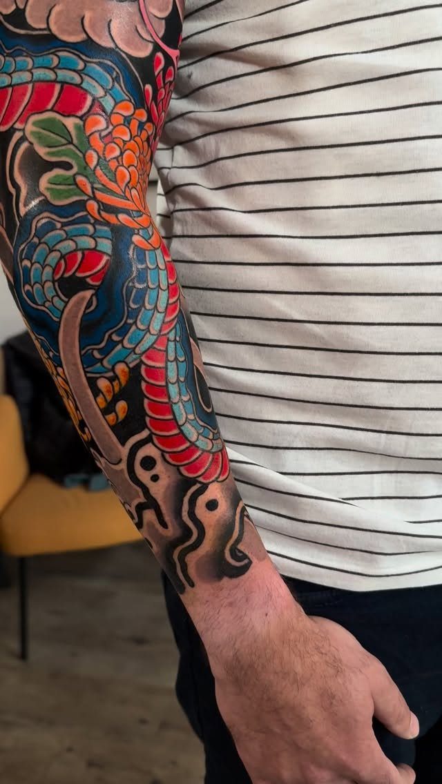 Japanese snake tattoo sleeve with red and blue scales and orange flowers