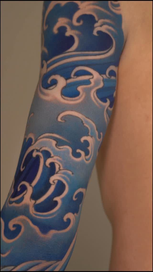 Blue and white Japanese wave tattoo covering a person's entire arm sleeve.