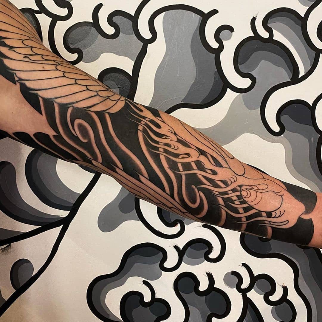 Japanese style tattoo on an arm featuring black wind bars and flowing waves.