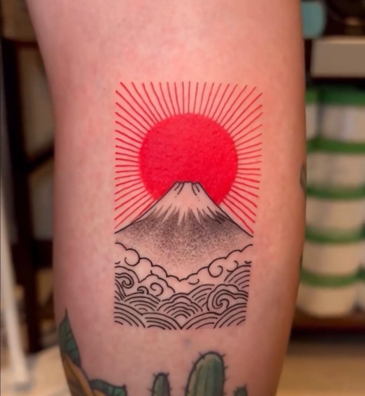 Tattoo of a red sun over Mount Fuji with traditional Japanese waves.