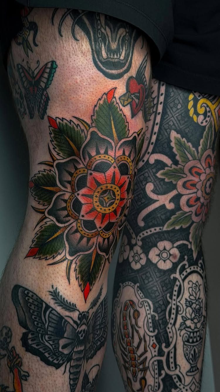 Legs with colorful American traditional tattoos featuring a large flower and a moth.
