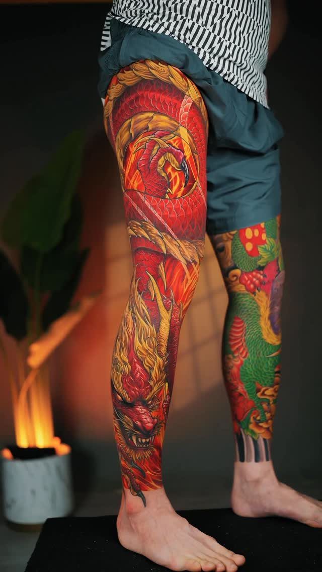 Detailed red and gold dragon tattoo covering a person's entire right leg sleeve.