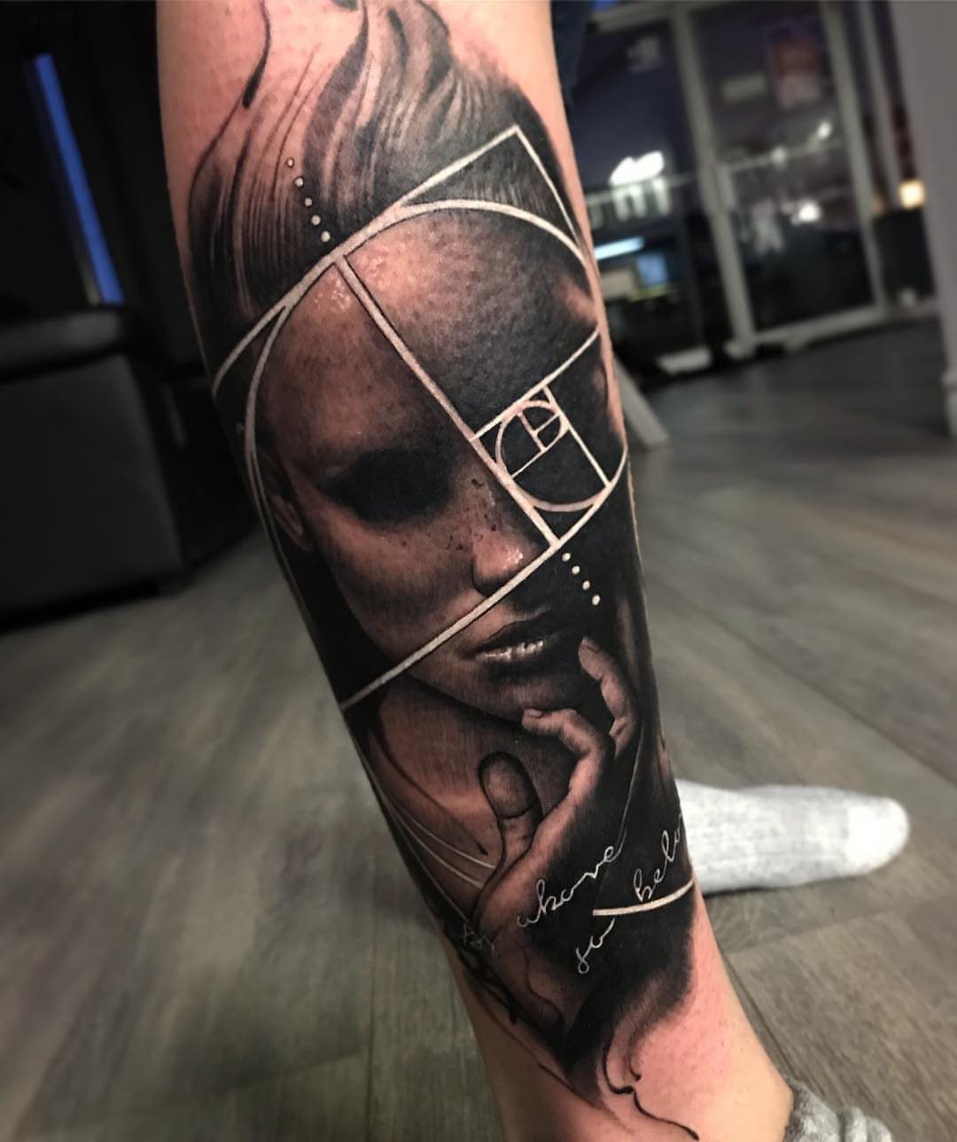 Black and grey realism tattoo of a woman's face with geometric lines on leg