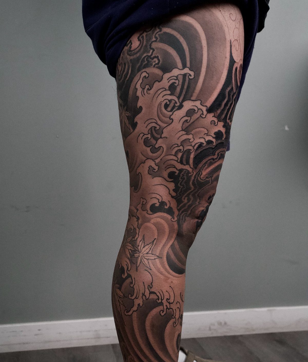 Leg sleeve tattoo featuring detailed black and grey crashing ocean waves and a star.