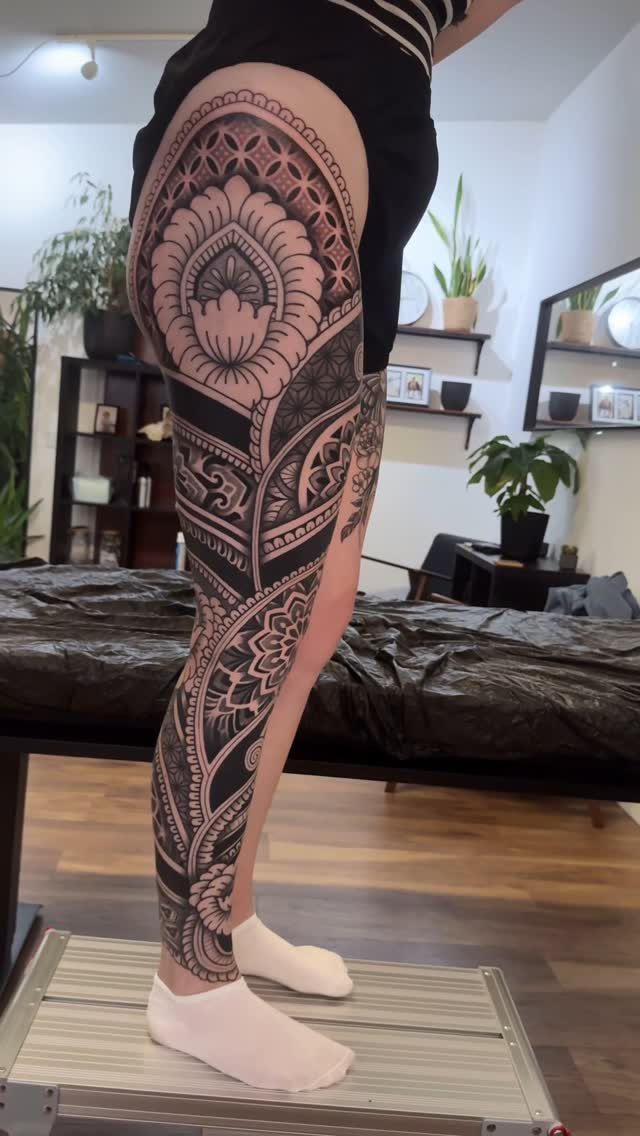 Full leg sleeve tattoo with intricate black ink mandala and geometric patterns on a woman.