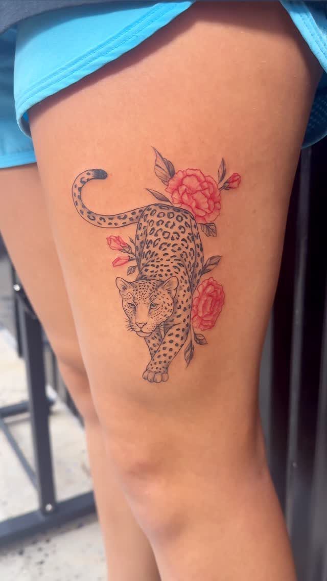 Leopard and red rose tattoo on a woman's upper leg
