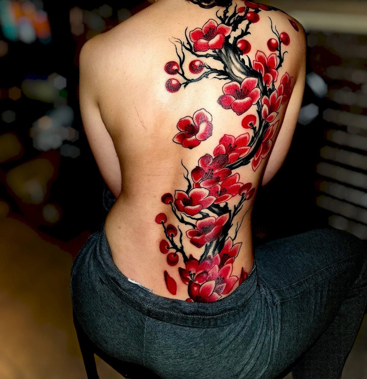 Red cherry blossom tattoo extending down a person's back to the lower back.