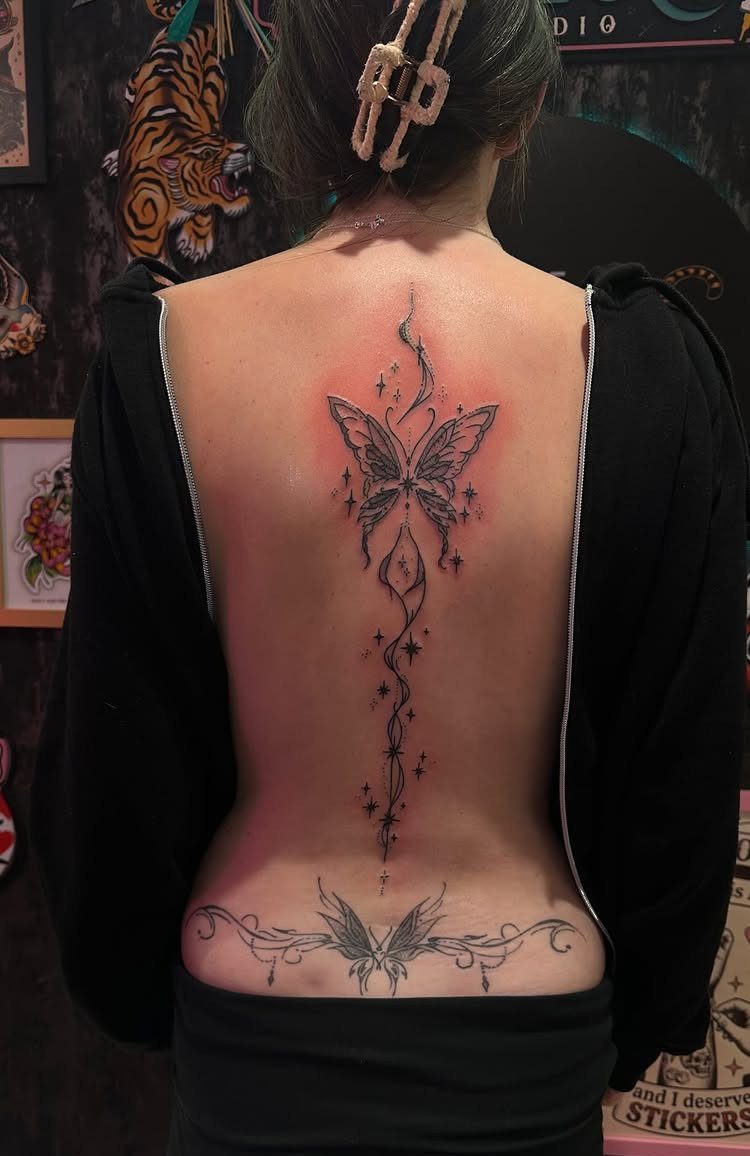 Butterfly tattoo on the lower back and a larger butterfly on the spine.