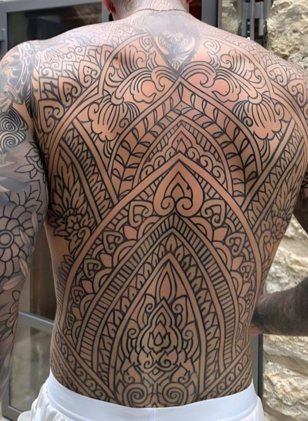 Large intricate black ink mandala tattoo covering a man's entire back
