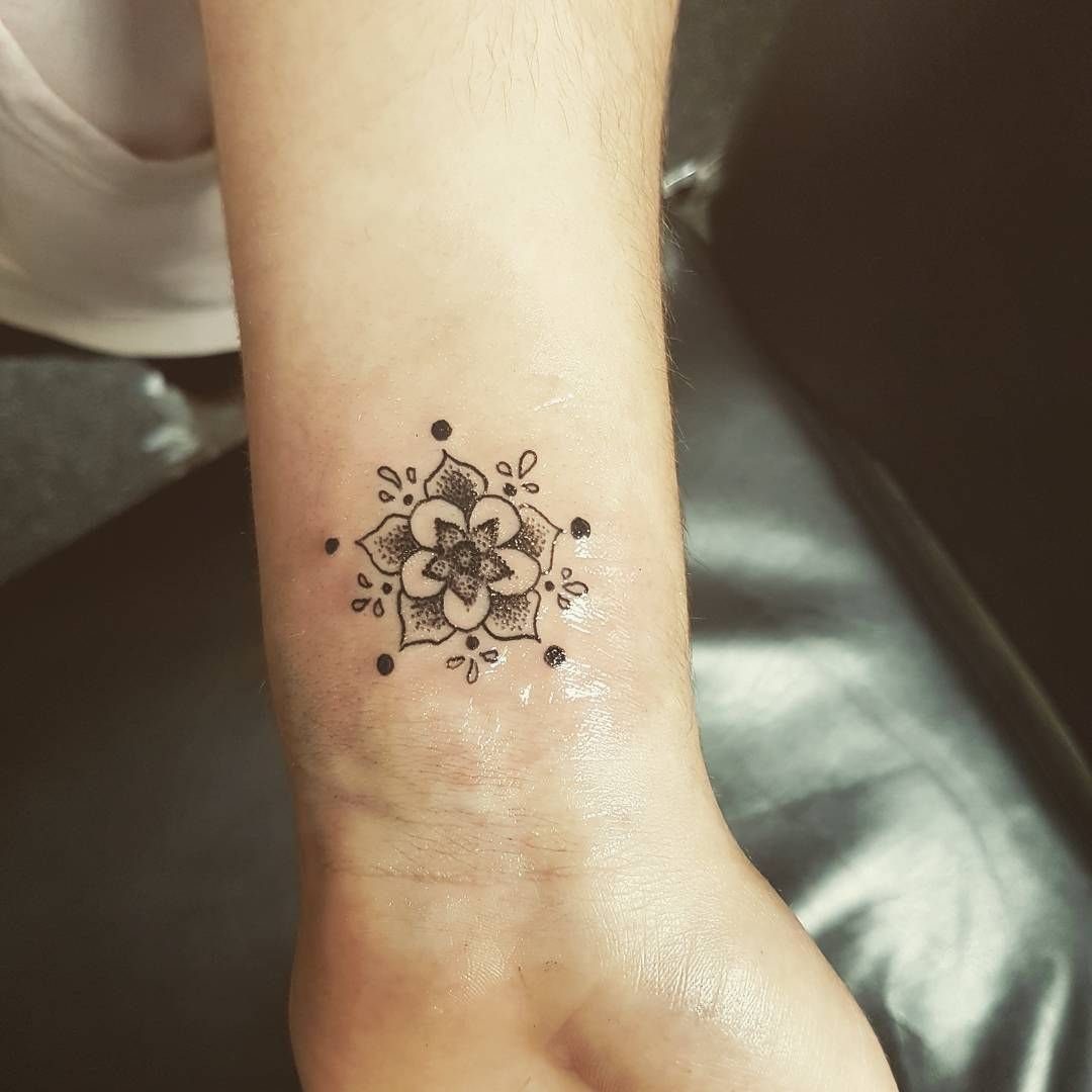 Small black ink mandala tattoo on a person's inner wrist.