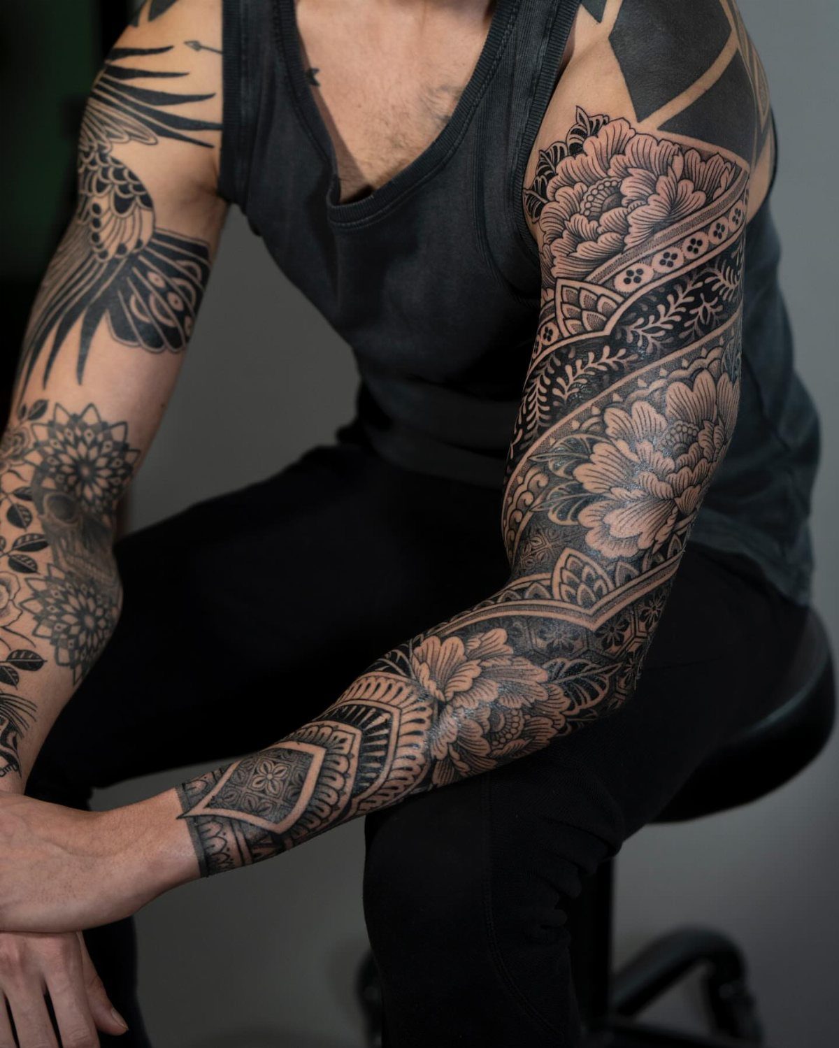 Full arm sleeve tattoos with floral and geometric mandala patterns on a man.