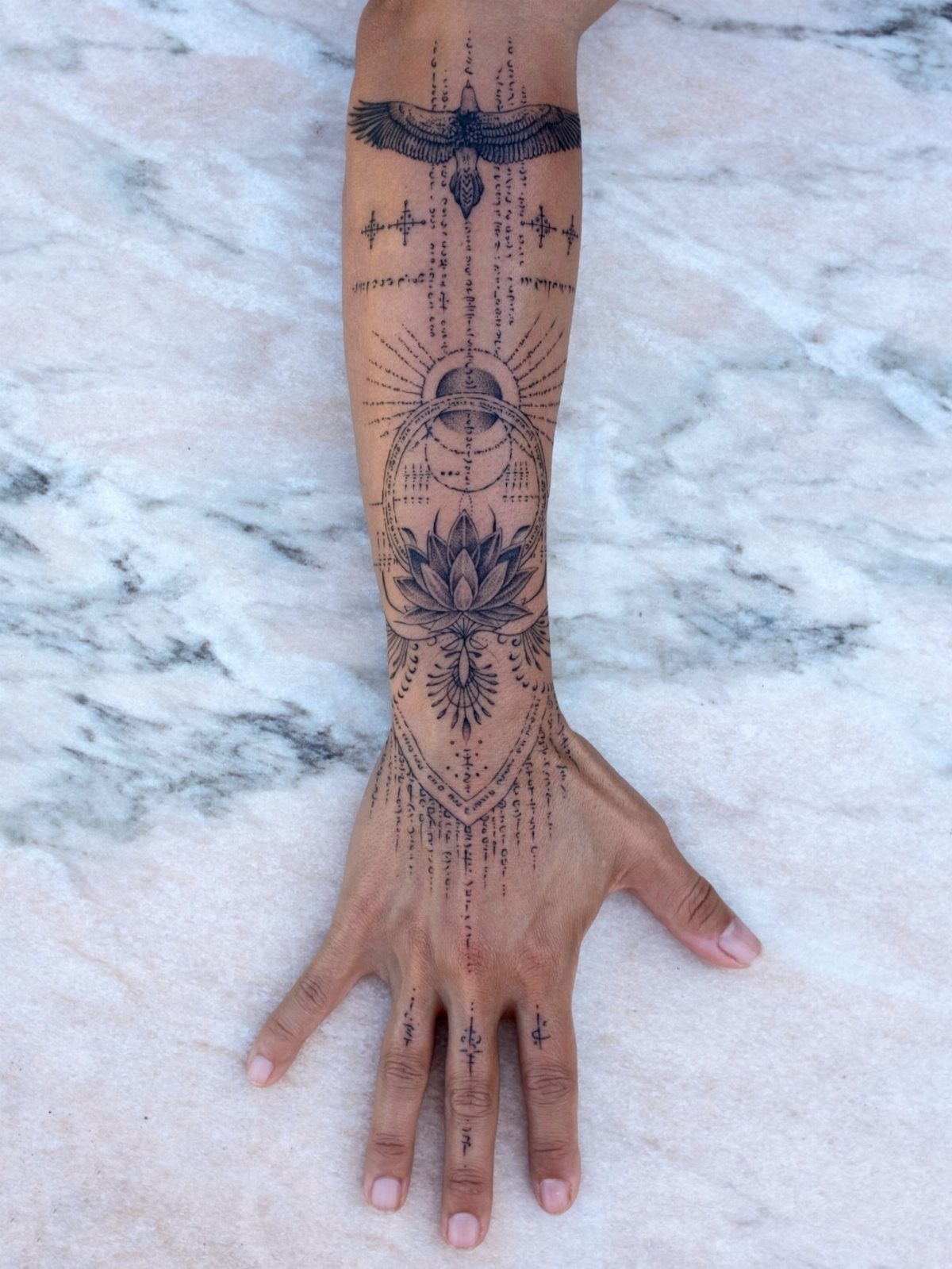 Forearm and hand tattoo featuring a detailed lotus mandala and geometric patterns.