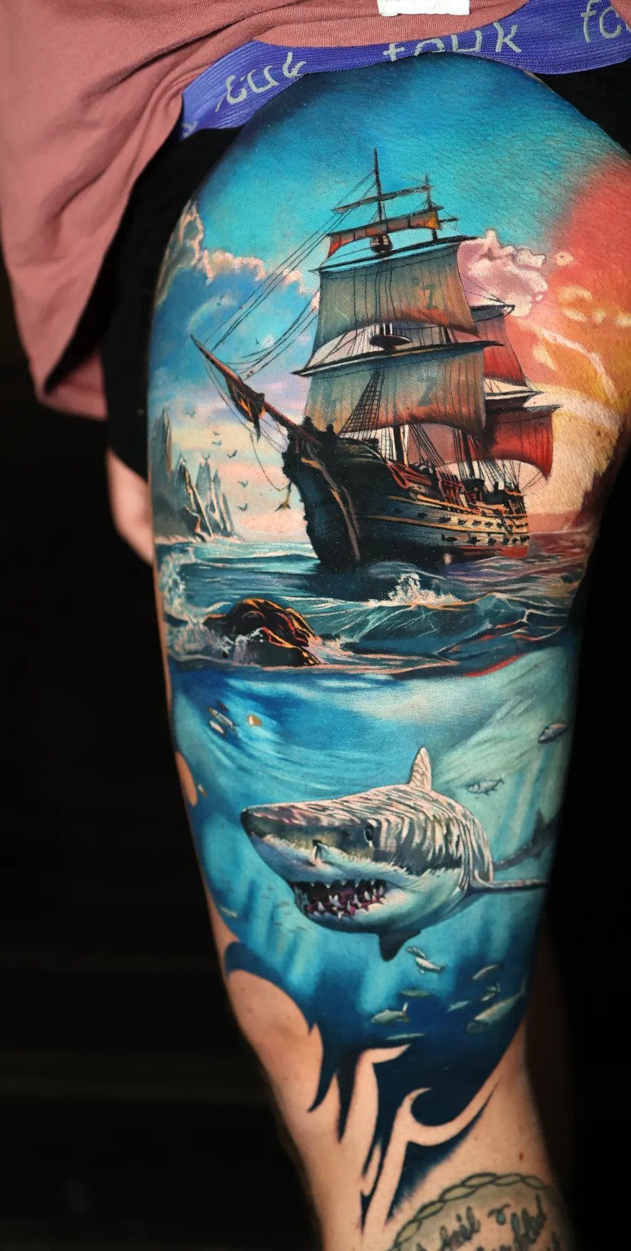 Half leg sleeve tattoo featuring a pirate ship above and a shark below.
