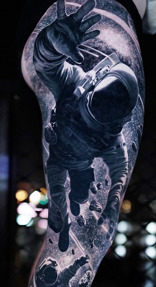 Astronaut floating in a starry cosmic space tattoo on a man's leg