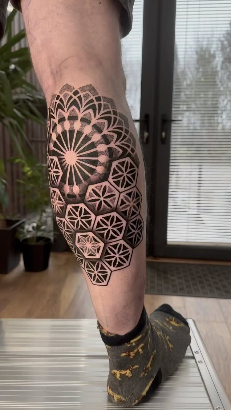 Man's calf tattoo featuring a black ink mandala and geometric hexagonal patterns.