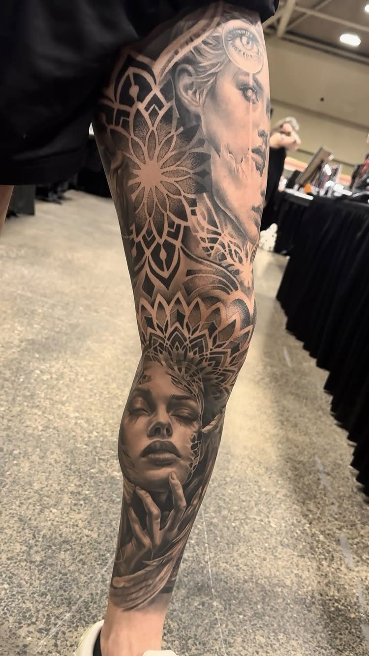 Detailed leg tattoo featuring realistic female faces and geometric mandala patterns in black ink.