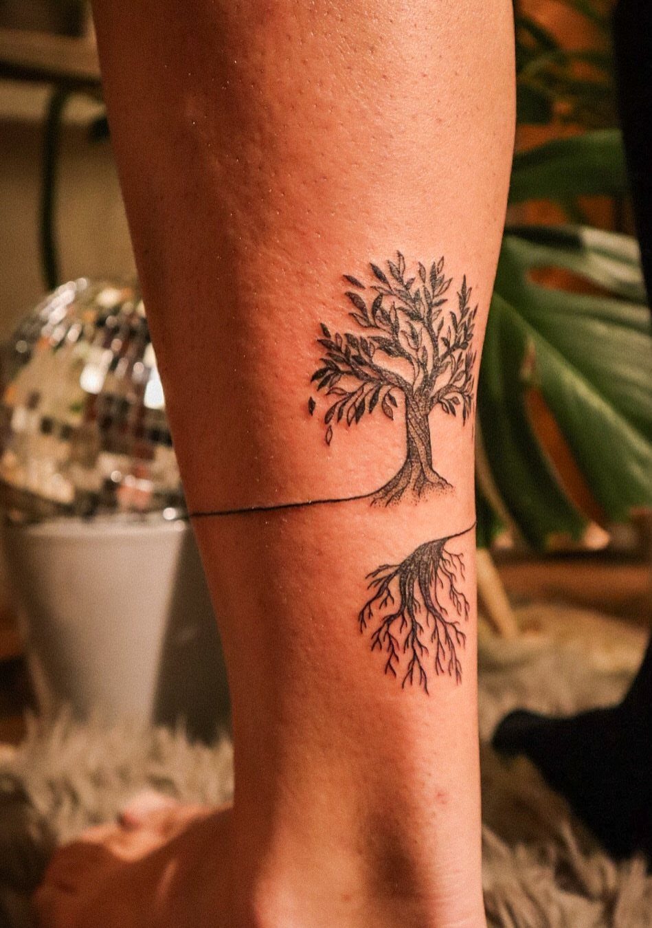 Tree of life tattoo on a lower leg with detailed roots and branches.