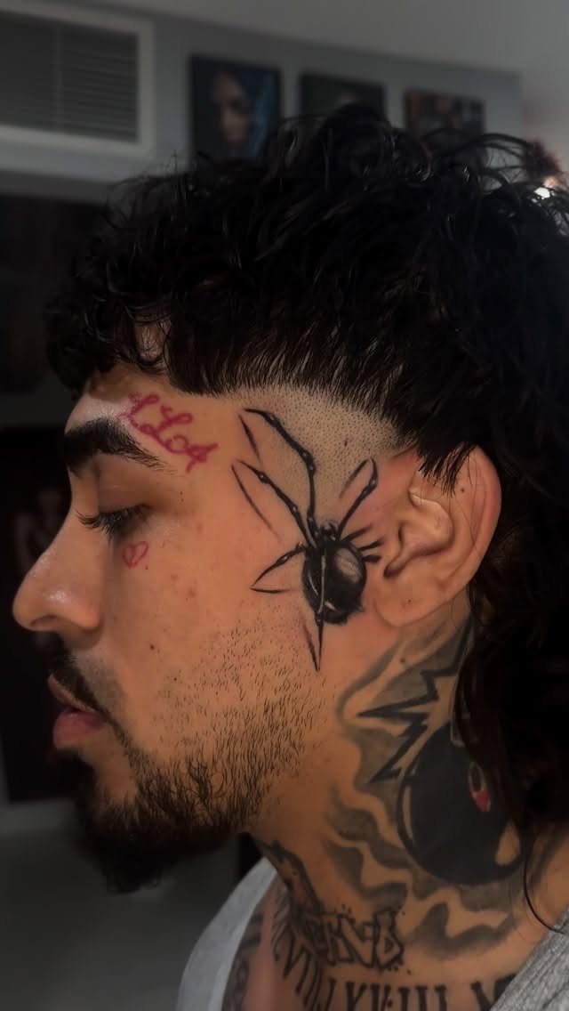 Man with a large black spider tattoo on his cheek and temple.