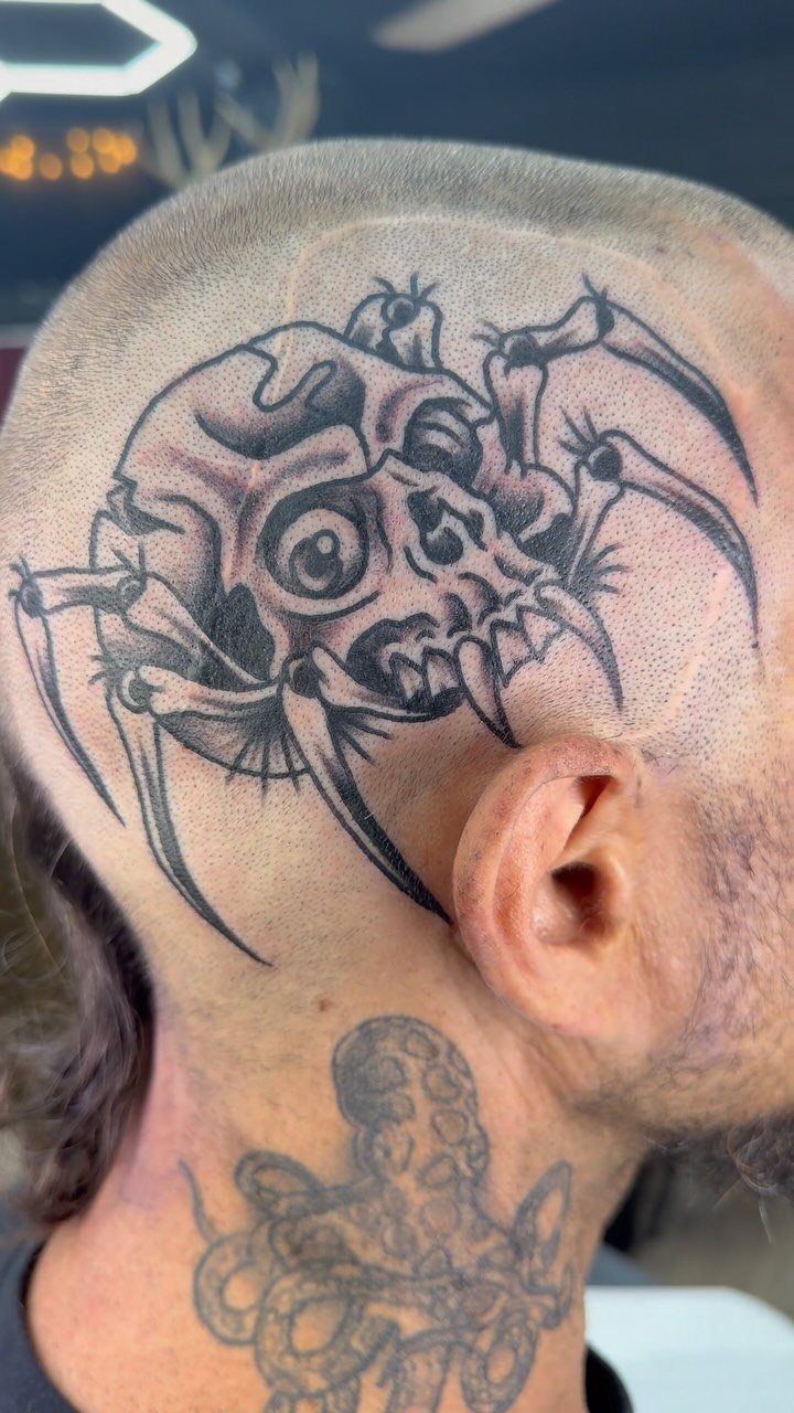 Skull with spider legs tattoo on the side of a man's head