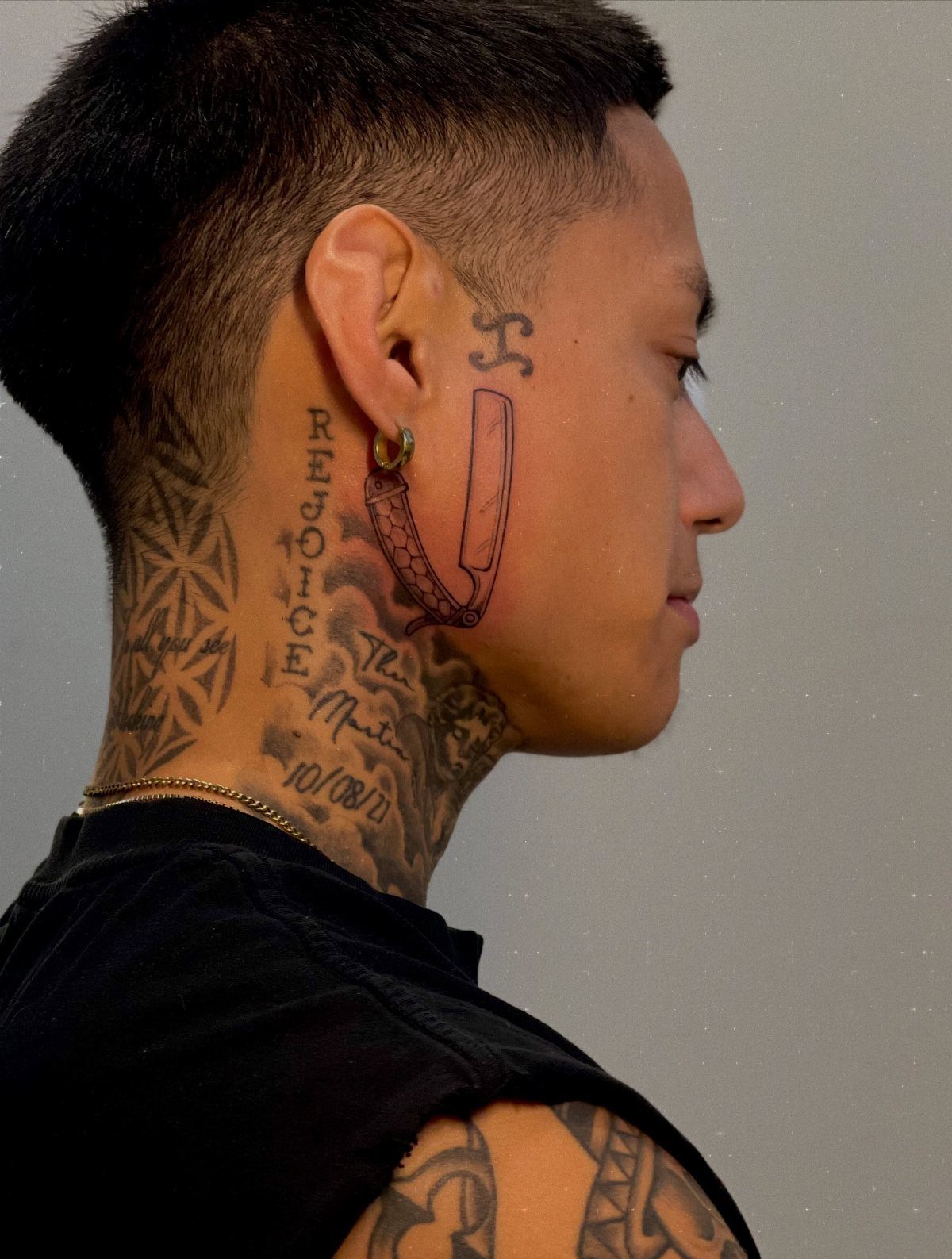 Man with a straight razor tattoo on his cheek and neck tattoos