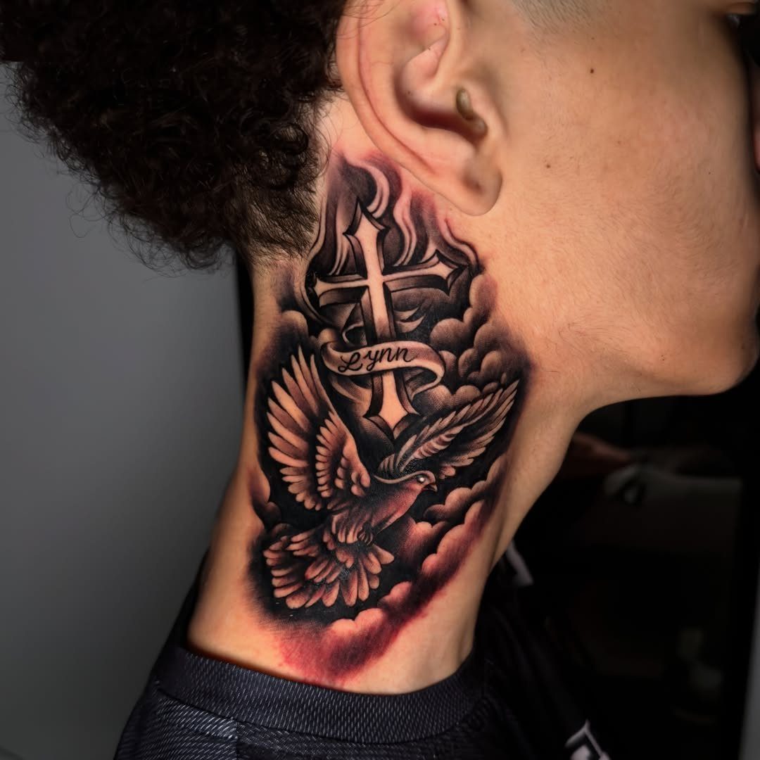 Neck tattoo of a cross and flying bird with a name ribbon