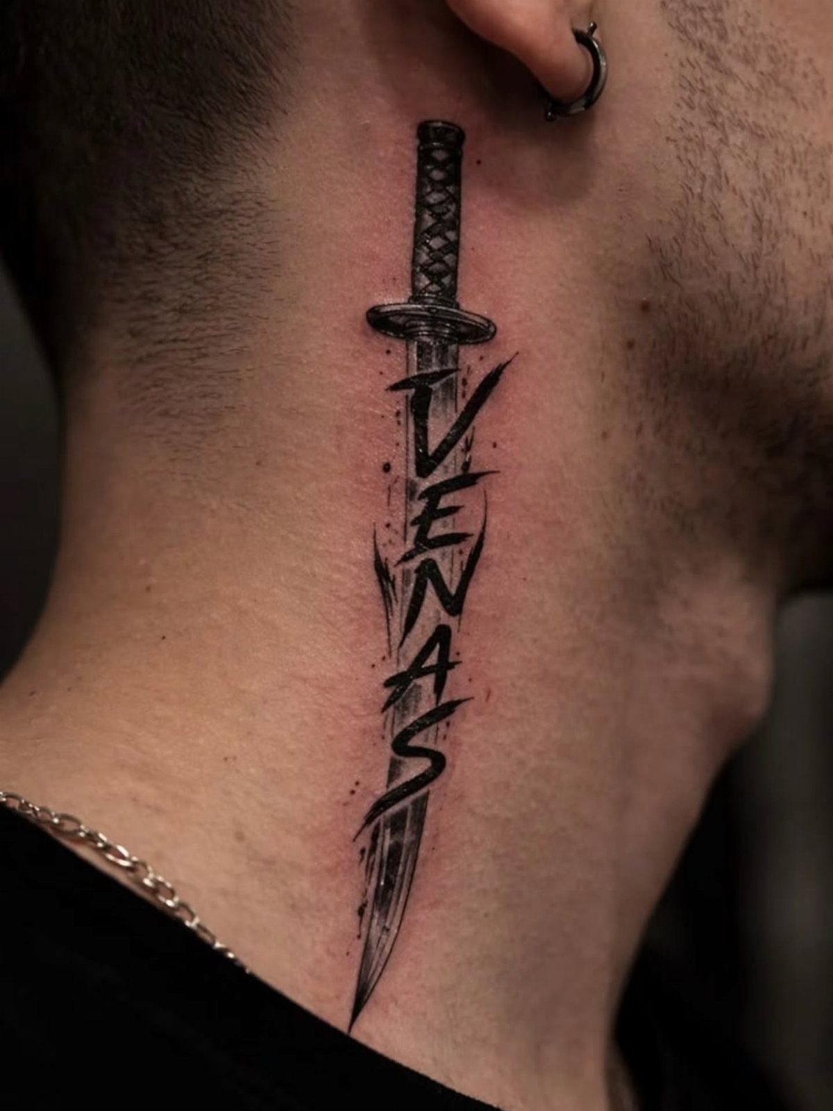 Man's neck tattoo of a black dagger with the word VENAS on the blade.