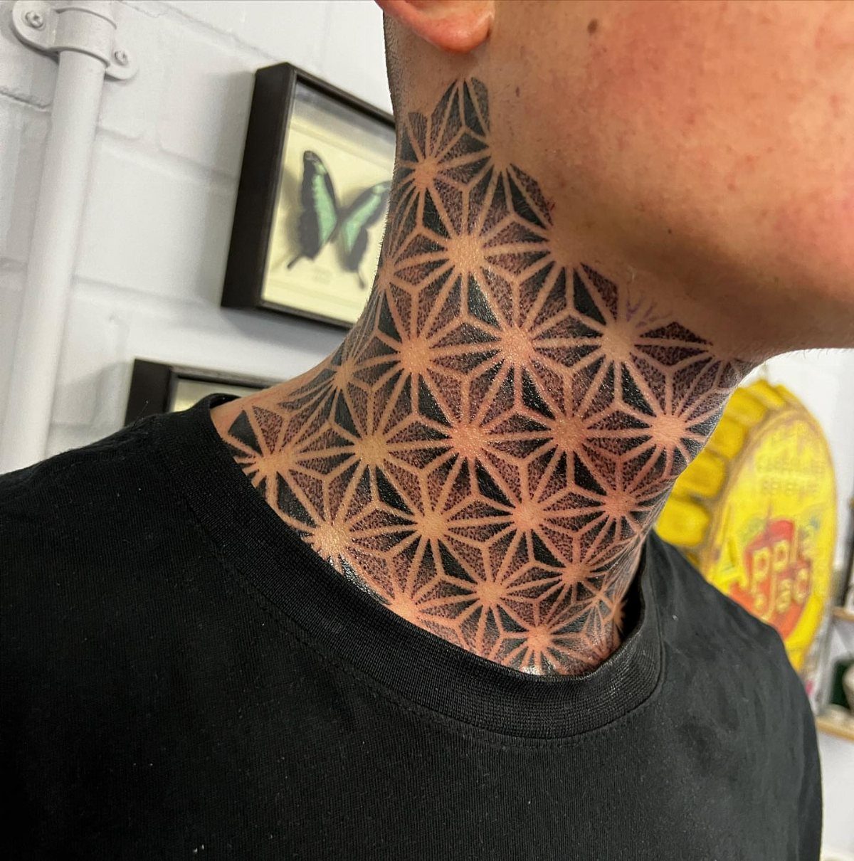 Man's neck with a black ink geometric triangle pattern tattoo.