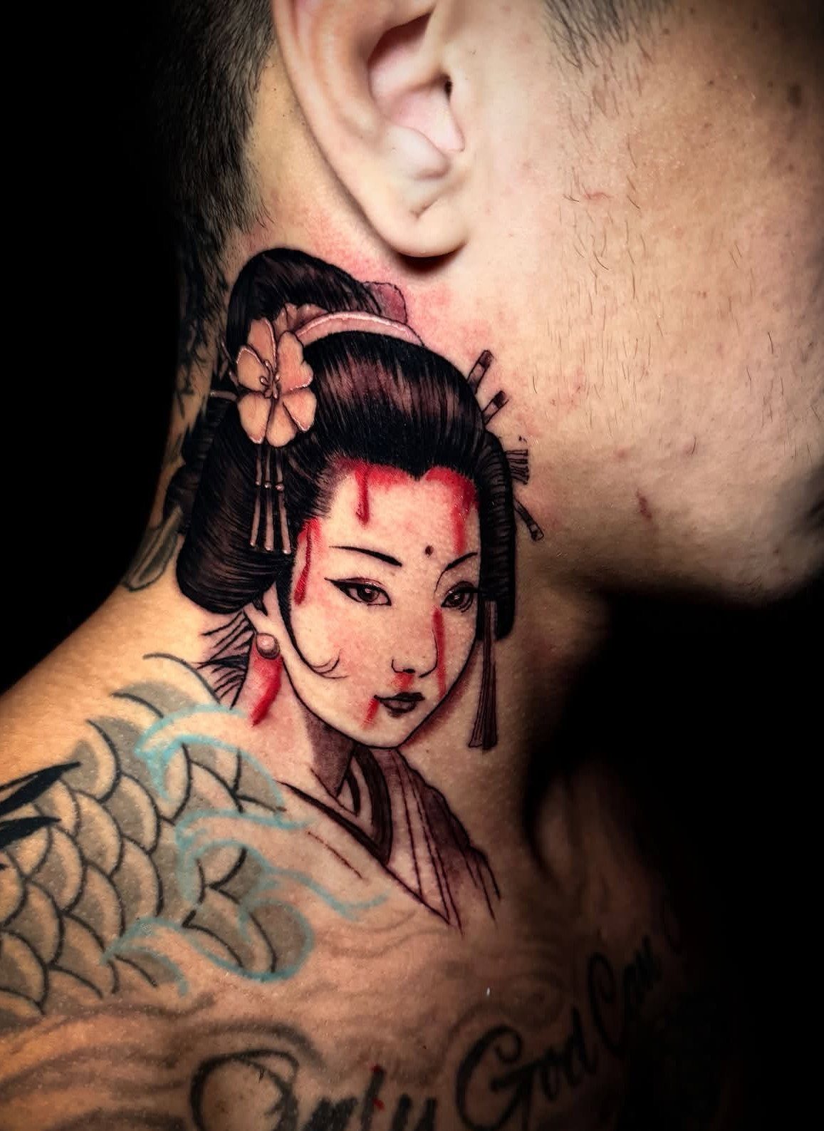 Geisha tattoo with red accents on a man's neck and shoulder area.