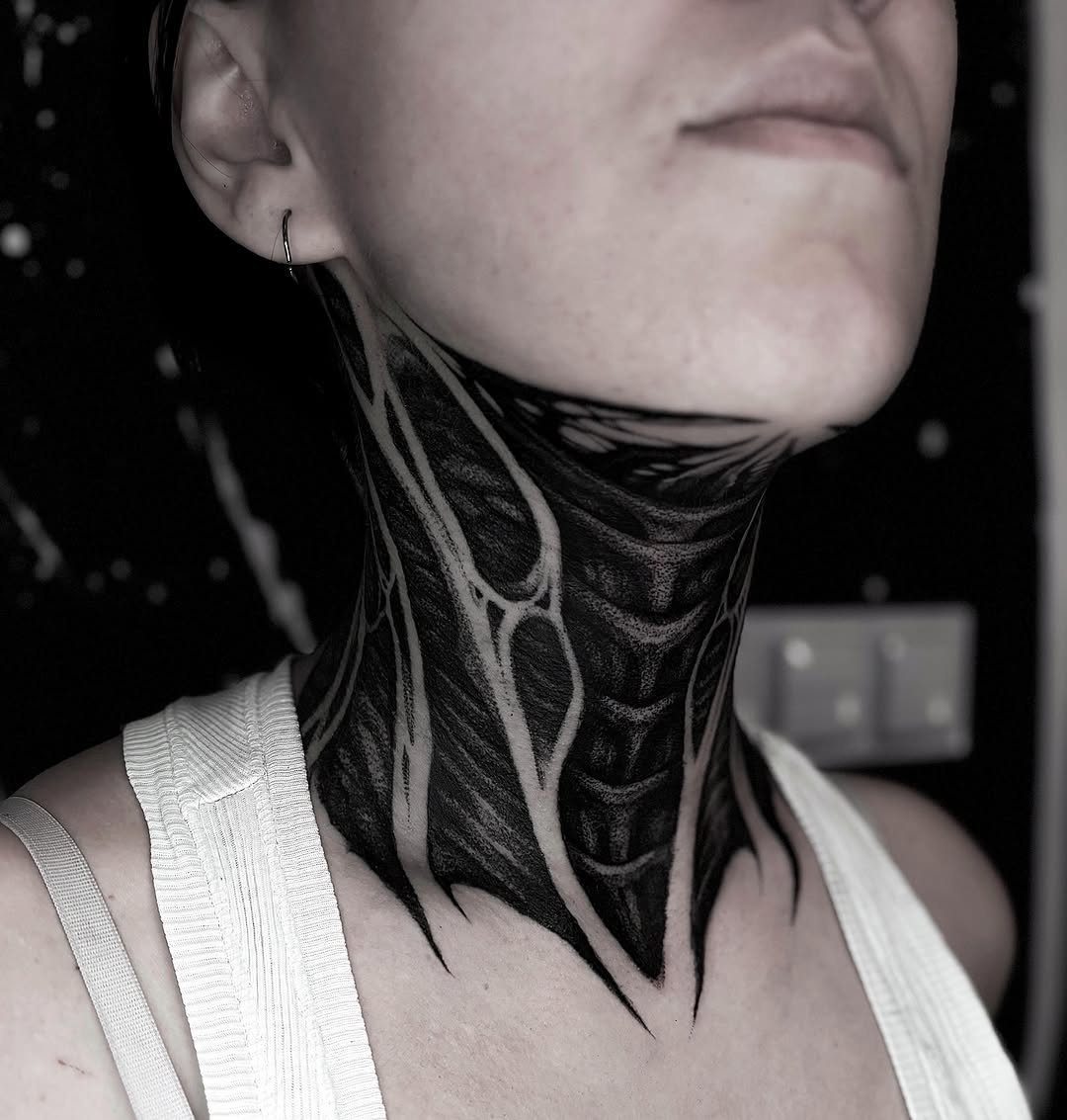Woman's neck with a large, intricate black ink biomechanical tattoo covering the area.