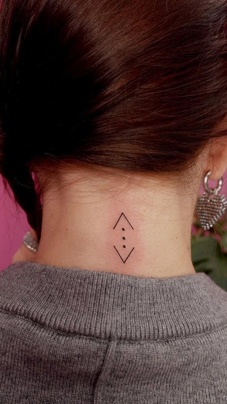 Small black diamond tattoo with three dots on the back of a woman's neck