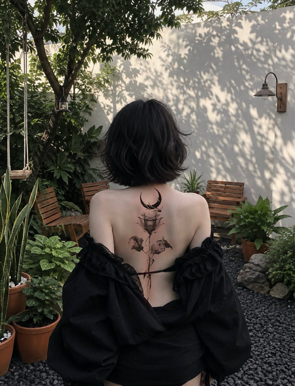 Woman with short dark hair showing a floral and moon tattoo on her back