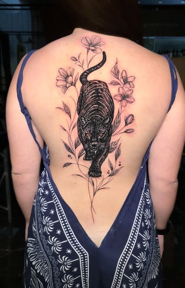 Woman's back with a large black ink panther and flower tattoo.