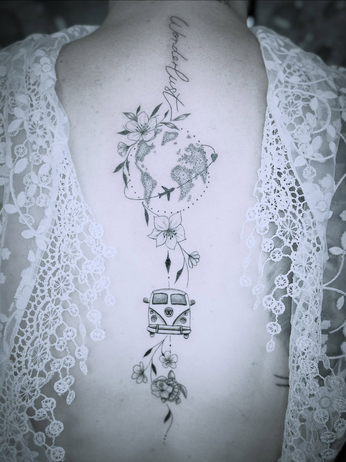World map tattoo with flowers and a camper van on a woman's back