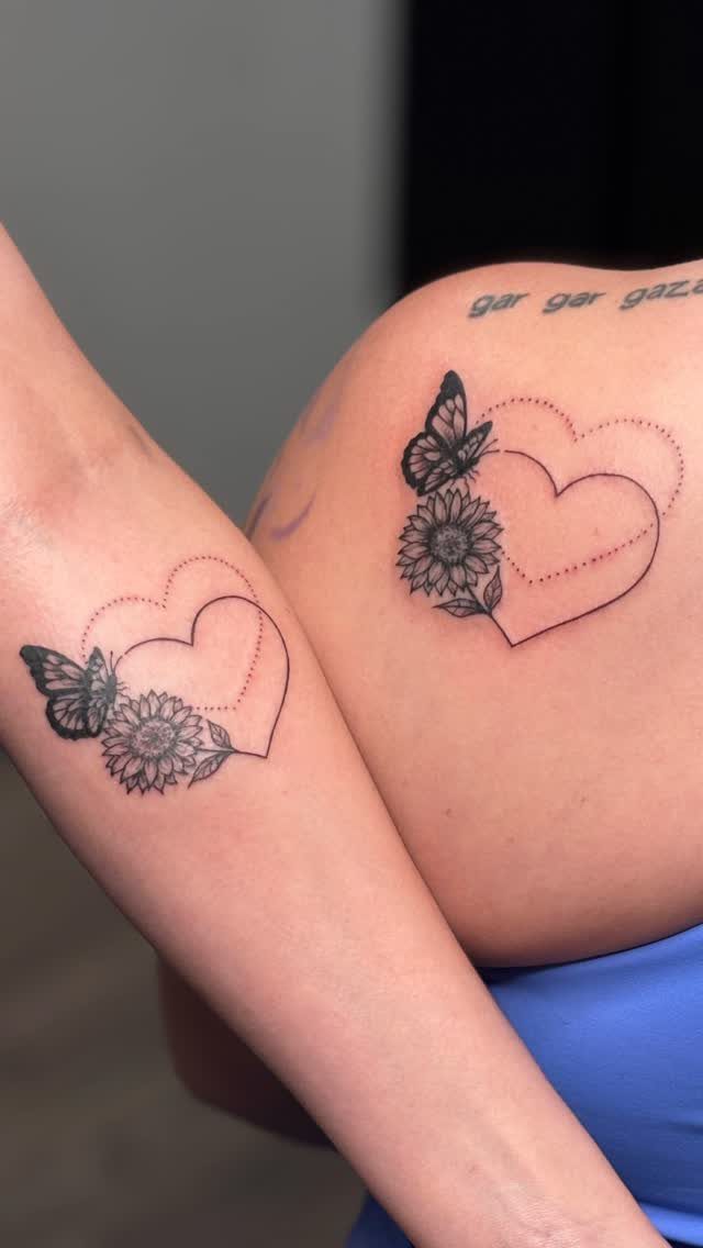 Matching heart tattoos with sunflowers and butterflies on a shoulder and arm.