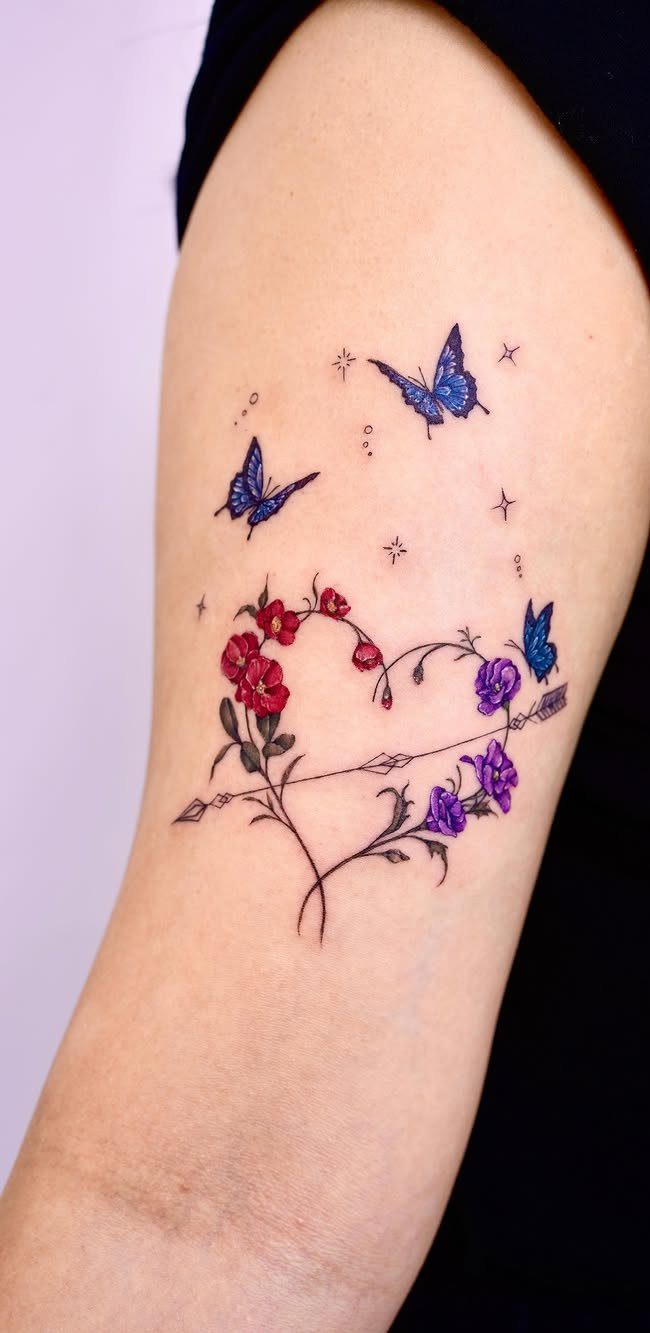Floral heart tattoo with an arrow and blue butterflies on an arm