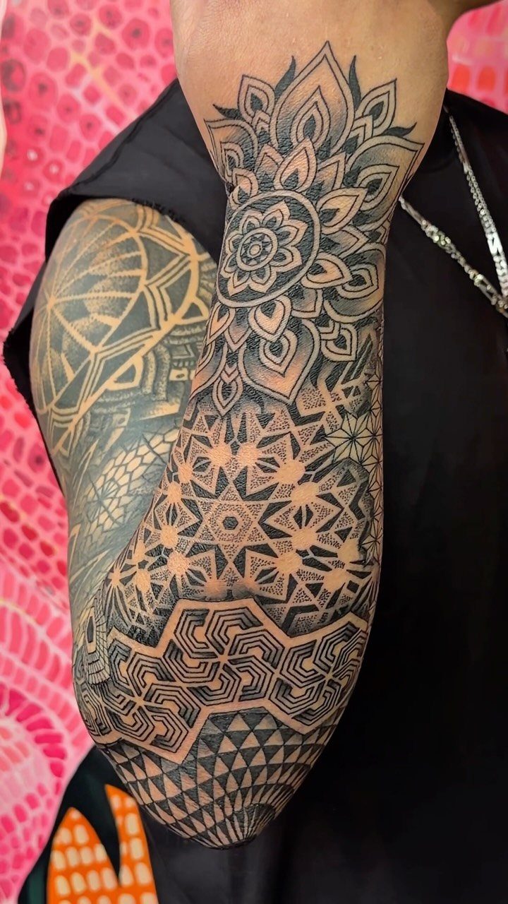 Geometric mandala and intricate pattern tattoos on a man's arm and forearm.