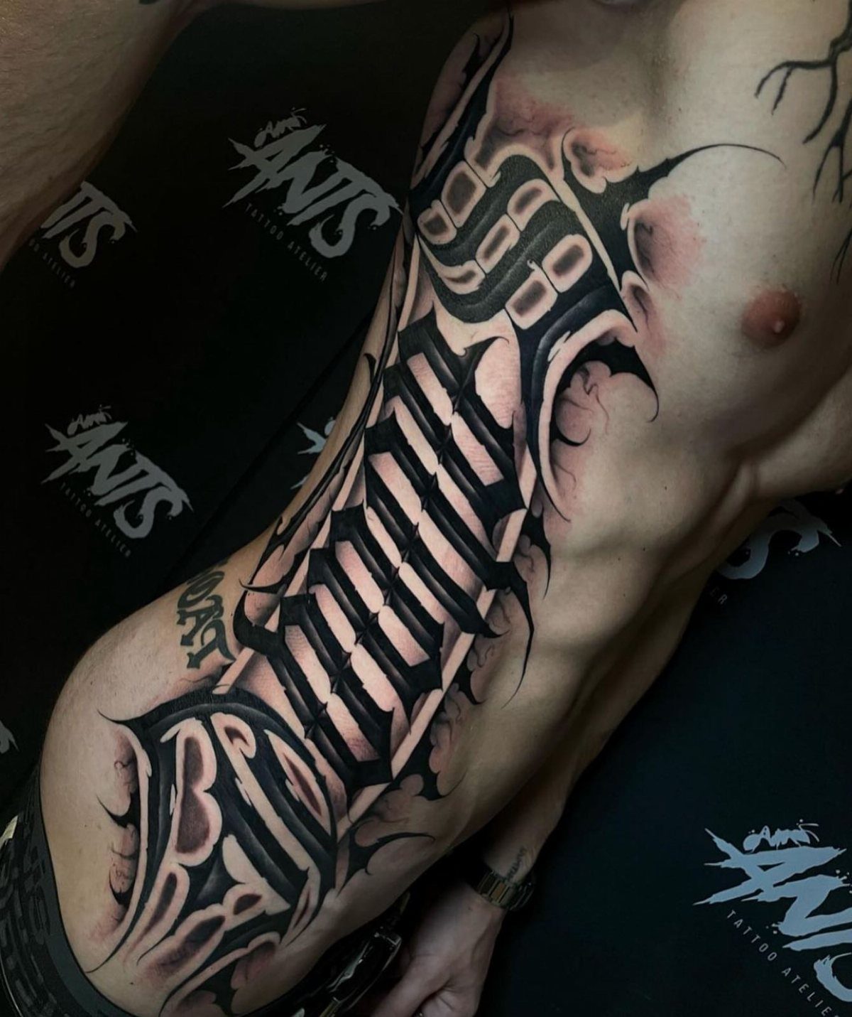 Large gothic style black and grey tattoo on a man's rib cage