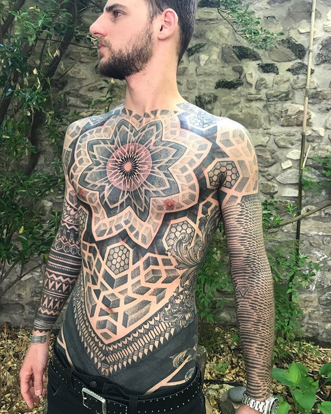 Man with a large geometric mandala tattoo covering his chest and rib area.